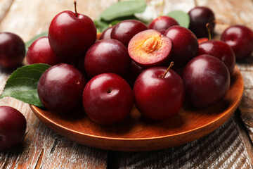 Whole and cut cherry plums on color wooden table, closeup