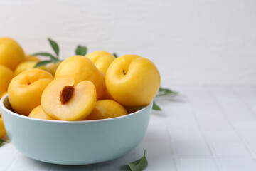 Ripe yellow cherry plums on white tiled table, closeup. Space for text