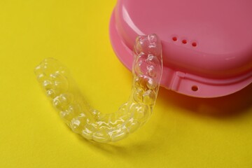 One clear aligner and retainer case on yellow background, closeup