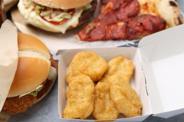 Different delicious fast food on grey table, closeup