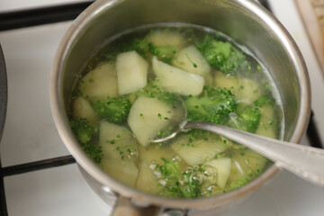 potatoes with broccoli are boiled in a saucepan on the stove