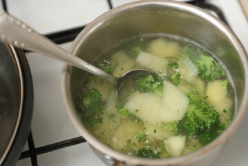 potatoes with broccoli are boiled in a saucepan on the stove