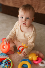 Little cute baby playing with toys sitting on the carpet