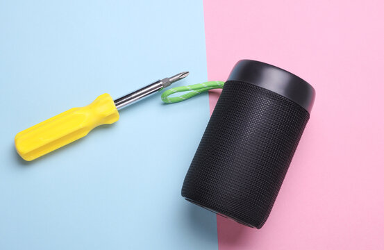 Screwdriver and bluetooth speaker on blue pink background