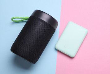 Wireless bluetooth stereo speaker and power bank on blue pink background. Top view