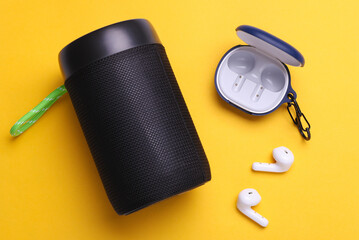 Wireless bluetooth stereo speaker with earphones on yellow background. Top view