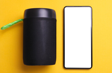 Wireless bluetooth stereo speaker with smartphone on yellow background. Top view