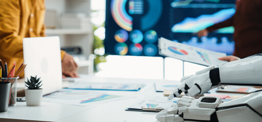 A modern workspace showcasing the integration of robotics in business, featuring digital charts, collaborative efforts, and innovative technology for strategic planning.Noogenesis