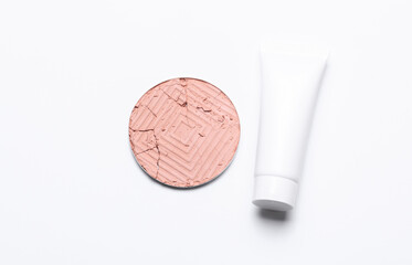 Crushed eyeshadow for makeup and cream tube. Cosmetic product sample on white background. Minimalism beauty concept. Top view. Creative layout