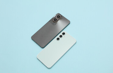 Two smartphones with dual and triple cameras on blue background