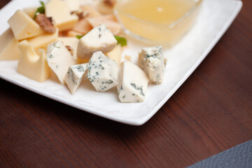 Different types of cheese on a plate with honey