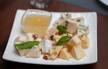 Different types of cheese on a plate with honey