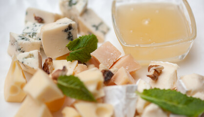 Different types of cheese on a plate with honey