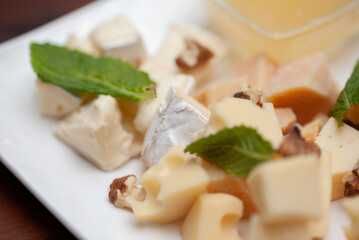 Different types of cheese on a plate with honey