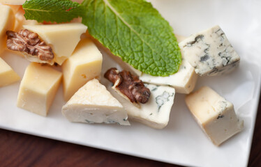 Different types of cheese on a plate with mint leaf