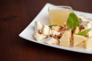 Different types of cheese on a plate with honey