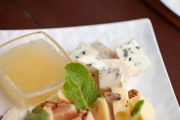 Different types of cheese on a plate with honey