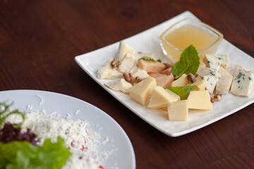 Different types of cheese on a plate with honey