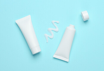 Mockup of white tube with smear of cream on blue background