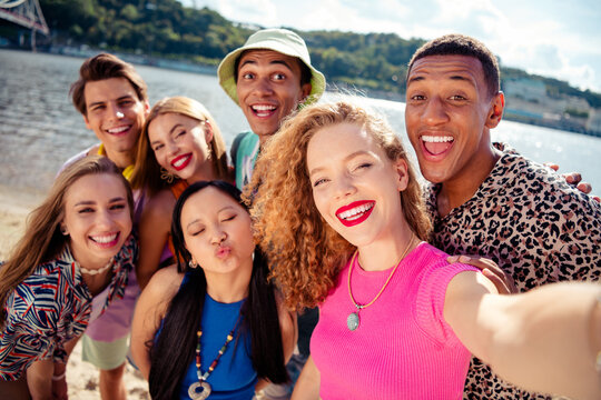 Joyful group of diverse friends enjoying a sunny day at the beach with laughter and smiles