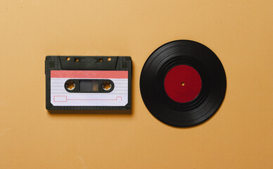 Retro vinyl record and audio cassette on yellow background