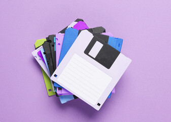 Stack of colored floppy disks on purple background. Computer technology 80s. Top view.