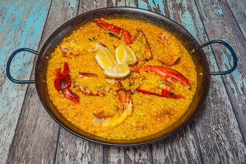 Lobster paella with whole shellfish as a garnish, served directly from the pan to the table