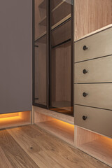 Smooth  wood walk-in wardrobe with pivoting glass doors and a central chest of drawers with...