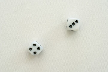 Two white dices on a white canvas, showing the numbers four and three.