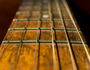 Close-up view of a well-worn acoustic guitar fretboard, showcasing the wood grain, strings, and frets.