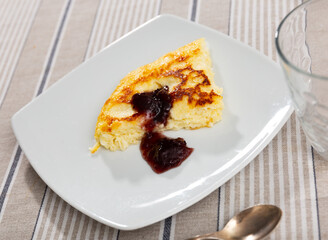 Appetizing piece of cottage cheese casserole served with jam for dessert