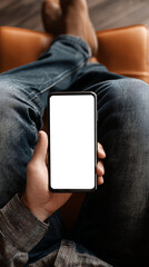 Person relaxing on a couch holding a smartphone with a blank white screen mobile phone hand