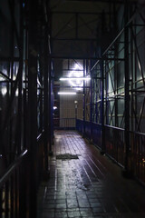 A dimly lit, covered walkway with metal scaffolding stretches into the night in Indonesia