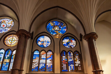 Fototapeta premium Colorful stained glass windows with abstract patterns allow colored light to enter the church. Gothic arches frame the windows.
