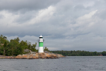 Marine channel marker on coastal rocks with green top, indicating the edge of the channel. Coastal navigation aid in Baltic sea, highlighting safety, marine guidance, and rocky shoreline