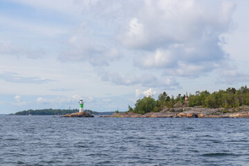 Marine channel marker on coastal rocks with green top, indicating the edge of the channel. Coastal navigation aid in Baltic sea, highlighting safety, marine guidance, and rocky shoreline