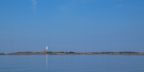 Small lighthouse with adjacent house on rocky islet in the Baltic Sea. Coastal scene in Finland with traditional maritime architecture, peaceful waters, and northern light