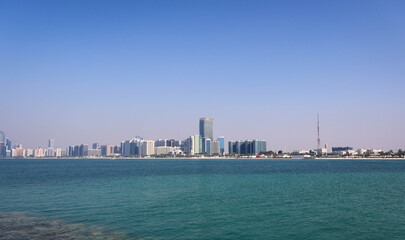 Naklejka premium Modern Abu Dhabi skyline with high-rise towers, wide streets, and city lights showcasing the UAE’s capital’s urban beauty.