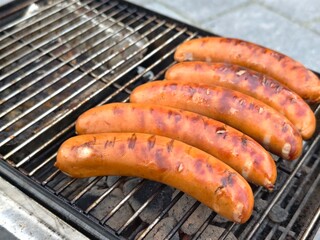 Grilling sausages on a barbecue for a summer cookout or picnic party with friends