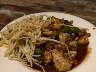 Delicious shrimp lo mein with noodles and vegetables on a white plate ready to eat