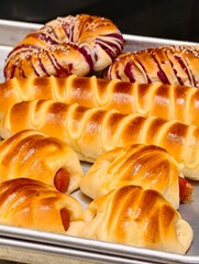 Delicious assortment of baked goods featuring sausage rolls and sweet purple yam bread