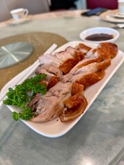 Delicious crispy pork belly slices served with soy sauce and fresh parsley garnish