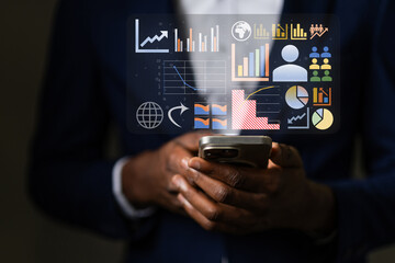 African businessman analyzing a holographic business intelligence dashboard on his smartphone, tracking global market data and managing company performance metrics.