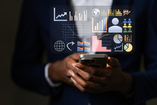 African businessman analyzing a holographic business intelligence dashboard on his smartphone, tracking global market data and managing company performance metrics.