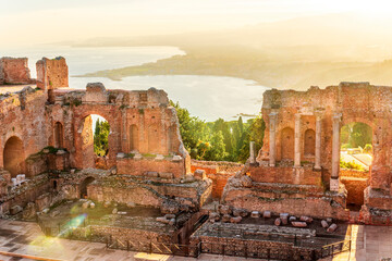 Panoramic view of a beautiful sunset in Ancient Theatre of Taormina in Sicily with antique italian town and mountain sunset on background. Holidays and sightseeing in Italy
