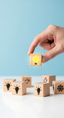 Hand placing a wooden cube with a glowing lightbulb symbol onto a surface with other cubes idea innovation