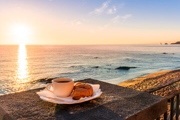concept of street outdoor breakfast with a cup of tea or coffee on a morning coast during sunrise. landscape of city embarkment with sea water and cloudy sky on background