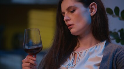 Sad woman at home night drink glass of wine alone watching photo album memories looking pictures thoughtful pensive female Caucasian girl relaxing upset drunk addict alcohol problem depression evening
