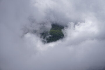 Obraz premium Dramatic View of Mountain Peaks Emerging Through Thick Clouds