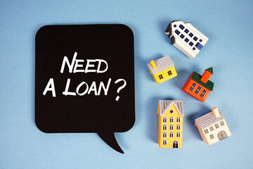 Need A Loan? text with house models on blue background